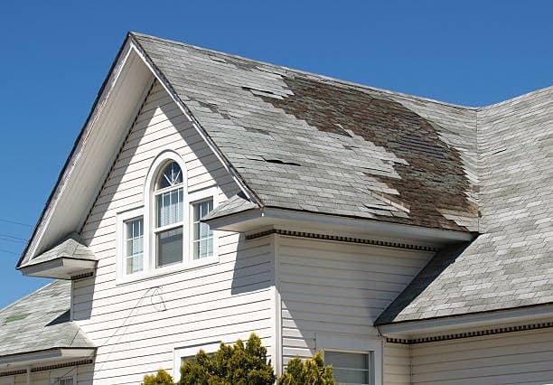 Professional roof repair technician working on damaged roof